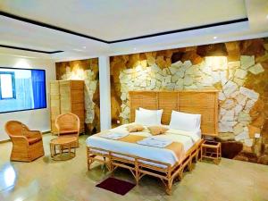 een slaapkamer met een groot bed en een stenen muur bij Ella Dream Mount in Ella