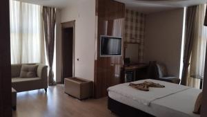 a bedroom with a bed and a chair and a television at LÜKS HOTEL in Mersin