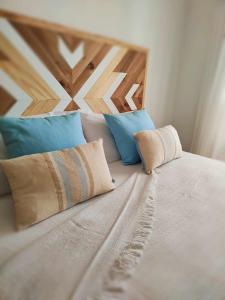a white bed with blue pillows on top of it at El Cotillo On The Beach by Momi Fuerteventura in Cotillo