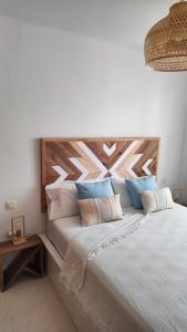 a bedroom with a large bed with a wooden headboard at El Cotillo On The Beach by Momi Fuerteventura in Cotillo