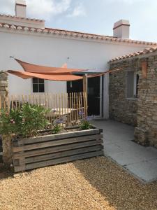 um pátio com uma mesa e um guarda-chuva numa casa em Les Agapanthes em Noirmoutier-en-l'lle