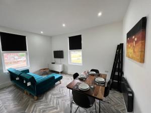 a living room with a table and a blue couch at Sleek & Stylish Spacious Apartment near Leeds City Centre in Headingley