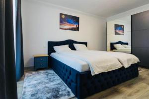 een slaapkamer met een groot bed met een blauw hoofdeinde bij Dominic Apartments Sighisoara in Sighişoara
