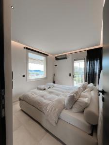 a white bedroom with a large bed with pillows at Lagonisi Luxury appartment 2 by the sea in Lagonissi