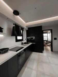 a kitchen with black cabinets and white counter tops at Lagonisi Luxury appartment 2 by the sea in Lagonissi