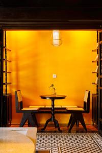 a table and chairs in a room with a yellow wall at De Stefano Coffee and Hotel in Phu Quoc +42 photos