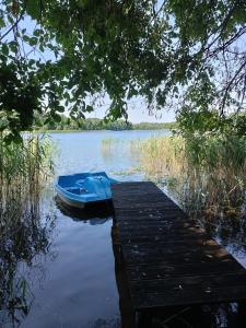 a blue boat sitting on the water next to a dock at Między Lasem a Wodą in Nowe Worowo