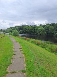 a path in the grass next to a river at Newbus Grange Lodge The Cottage in Darlington