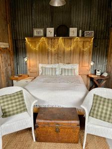 a bedroom with a bed with a wooden headboard and two chairs at The Pig and Sty in Hereford