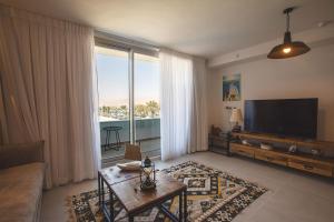 a living room with a couch and a television and a table at YalaRent New Sea side resort apartments in Eilat