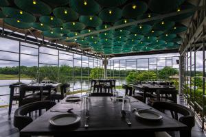 un comedor con mesas, sillas y ventanas en Starling River Resort Dandeli, en Dandeli