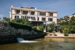 a building next to a river in front of a building at Veladrion Adults Exclusive Boutique Resort in Senj