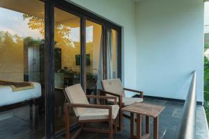 Pokój z 2 krzesłami i łóżkiem na balkonie w obiekcie Starling River Resort Dandeli w mieście Dandeli