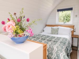 1 dormitorio con 1 cama y un jarrón de flores sobre una mesa en Ash, en Saltash