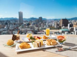 a plate of food on a table with a view of a city at Mitsui Garden Hotel Hiroshima in Hiroshima