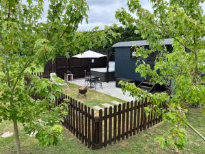 un patio trasero con una valla, una mesa y un cobertizo en Shepherds Hut with Hot Tub en Wells