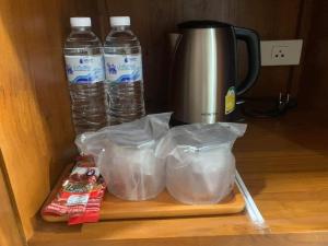 two bottles of water sitting on a cutting board next to a coffee maker at Na Sukhothai Hotel in Sukhothai