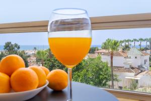 un vaso de zumo de naranja junto a un tazón de naranjas en Vistamarina A409 By IVI Real Estate en Torremolinos