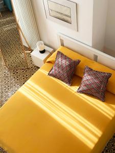 - un lit jaune avec deux oreillers dans l'établissement MARGHERITA 109, à Naples