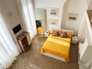 a small bedroom with a yellow bed and a television at MARGHERITA 109 in Naples