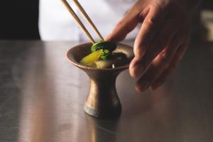 a person is stirring a small food dish with chopsticks at Ryokan Masuya in Ōda