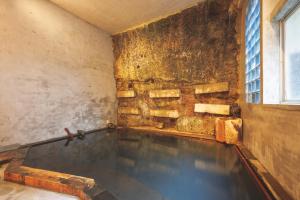 a swimming pool in a room with a brick wall at Ryokan Masuya in Ōda