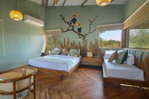 ein Schlafzimmer mit 2 Betten und ein Vogelbild an der Wand in der Unterkunft Tadoba Jungle Camp in Mohurli