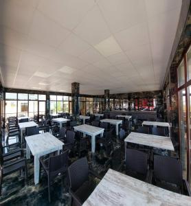 um restaurante vazio com mesas, cadeiras e janelas em Seaside Kobuleti Hotel em Kobuleti