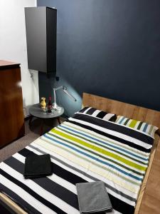 Una cama con una manta a rayas y una mesa en Calipso1, en Niš