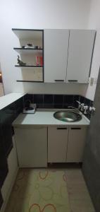 uma pequena cozinha com um lavatório e armários brancos em Calipso1 em Niš