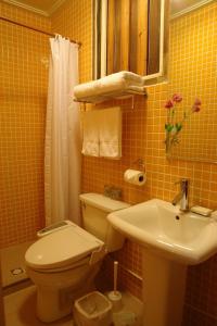 un bagno piastrellato giallo con servizi igienici e lavandino di PianoPiano B&B a Jincheng