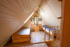 a attic room with two beds and a staircase at Namelis ant kranto - Alaušo Salos in Sudeikiai