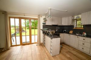 a kitchen with wooden cabinets and a large sliding glass door at Namelis ant kranto - Alaušo Salos in Sudeikiai
