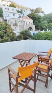 d'une table en bois et de deux chaises sur un balcon. dans l'établissement Serenity apartment, à Kóronos