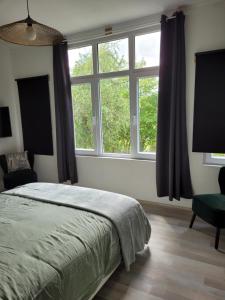 a bedroom with a bed and a large window at La Maison des Roses in Francorchamps