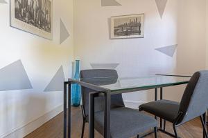 a dining room with a glass table and chairs at Le pied à terre d'ernest in Limoges