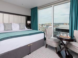 a bedroom with a bed and a large window at Grand Central Hotel Belfast in Belfast