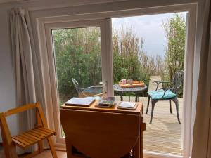 a desk in front of a sliding glass door with a patio at Cliff top Chalet with fantastic sea views in Cornwall. in Cawsand