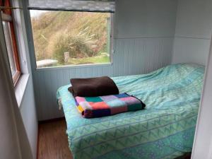 a small bedroom with a bed and a window at Cliff top Chalet with fantastic sea views in Cornwall. in Cawsand