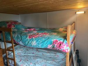 a bunk bed with a colorful comforter on it at Cliff top Chalet with fantastic sea views in Cornwall. in Cawsand