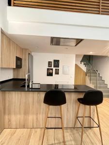 una cucina con ripiani neri e sgabelli da banco neri di WeRentVLC - Espectacular Loft Duplex 1 hab a Valencia