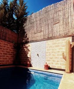 een zwembad voor een bakstenen muur met bij Villa Dar Bella in Aït Ali