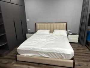 - une chambre dotée d'un grand lit avec des draps et des oreillers blancs dans l'établissement 4 Br Villa with cinema luxury, à Hanoï