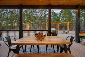 una mesa de madera con sillas en una terraza con parque infantil en All FORE The View Cabin in Hochatown en Broken Bow