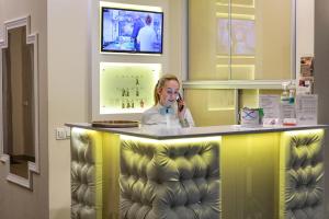 Kobieta rozmawiająca przez komórkę za ladą w obiekcie Dworek Różany Hotel & Restauracja w mieście Namysłów