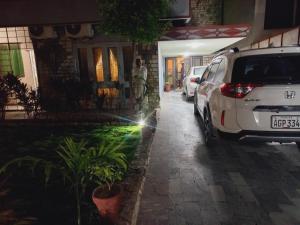 a man standing next to a white car parked on a street at Travel Inn islamabad in Islamabad