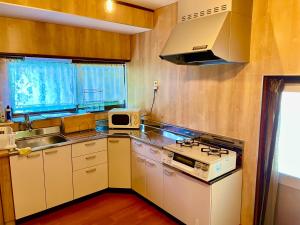 een kleine keuken met een fornuis en een magnetron bij 島の宿 近 別邸〜縁〜 in Oshima