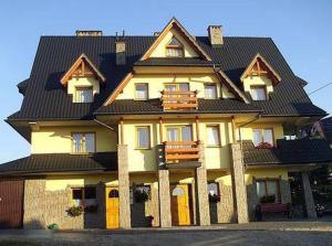 a large yellow house with a black roof at Pokoje u Hanki in Murzasichle