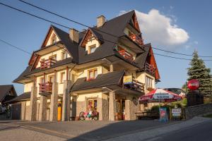 a large house with a black roof on a street at Pensjonat u Hanki in Murzasichle