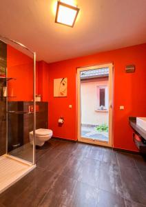 ein Badezimmer mit orangefarbenen Wänden, einem WC und einem Fenster in der Unterkunft Ferienhaus Conradshöh in Ilmenau